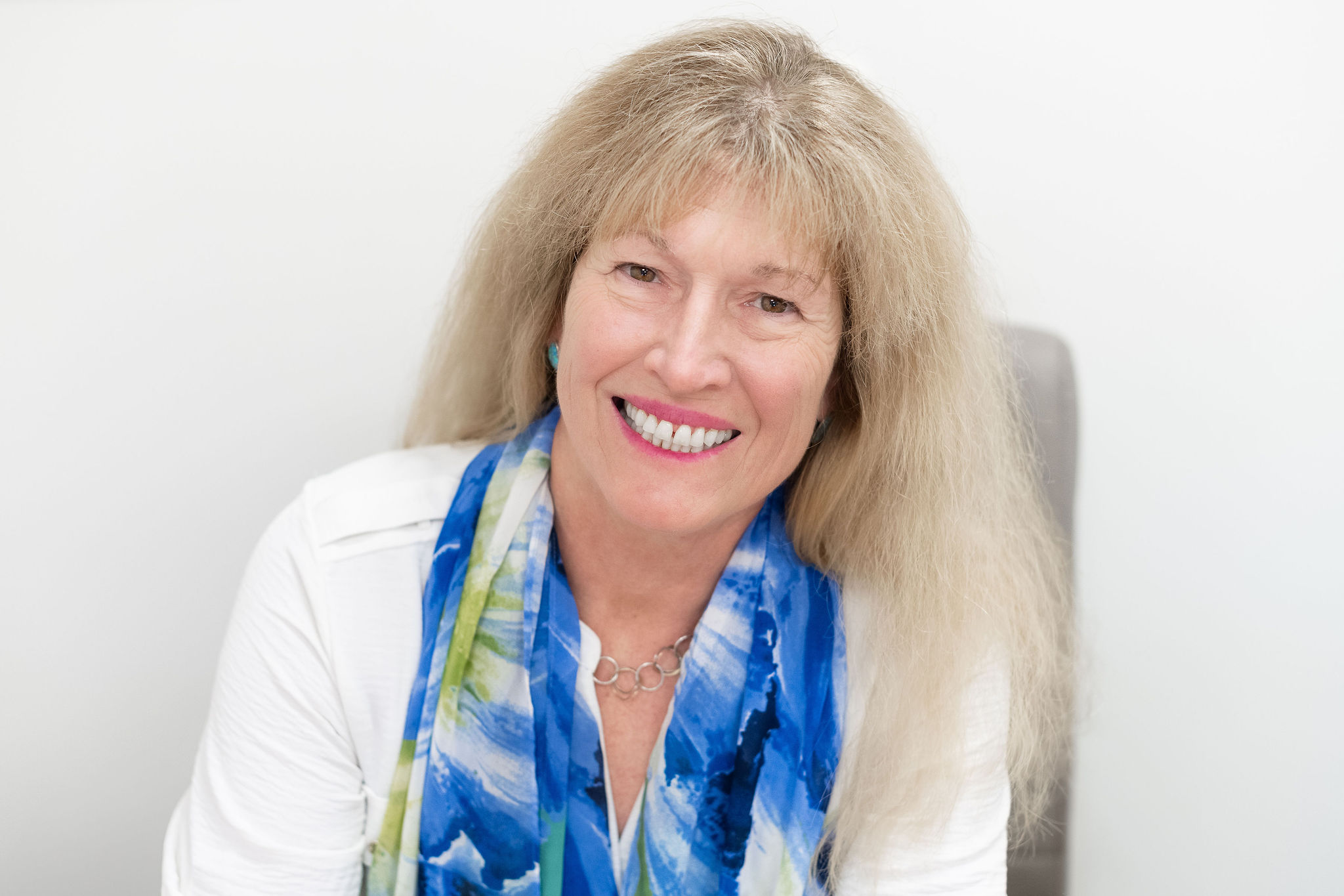Dr. Lori Zaremski, PhD, LEP, smiling in a white blouse and blue patterned scarf