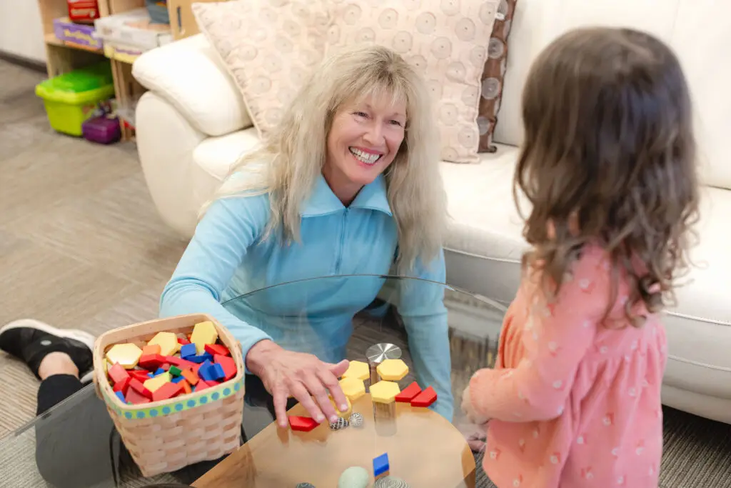 Therapist Lori Zaremski at The Light Center in South Bay guiding a child through play-based learning with colorful blocks