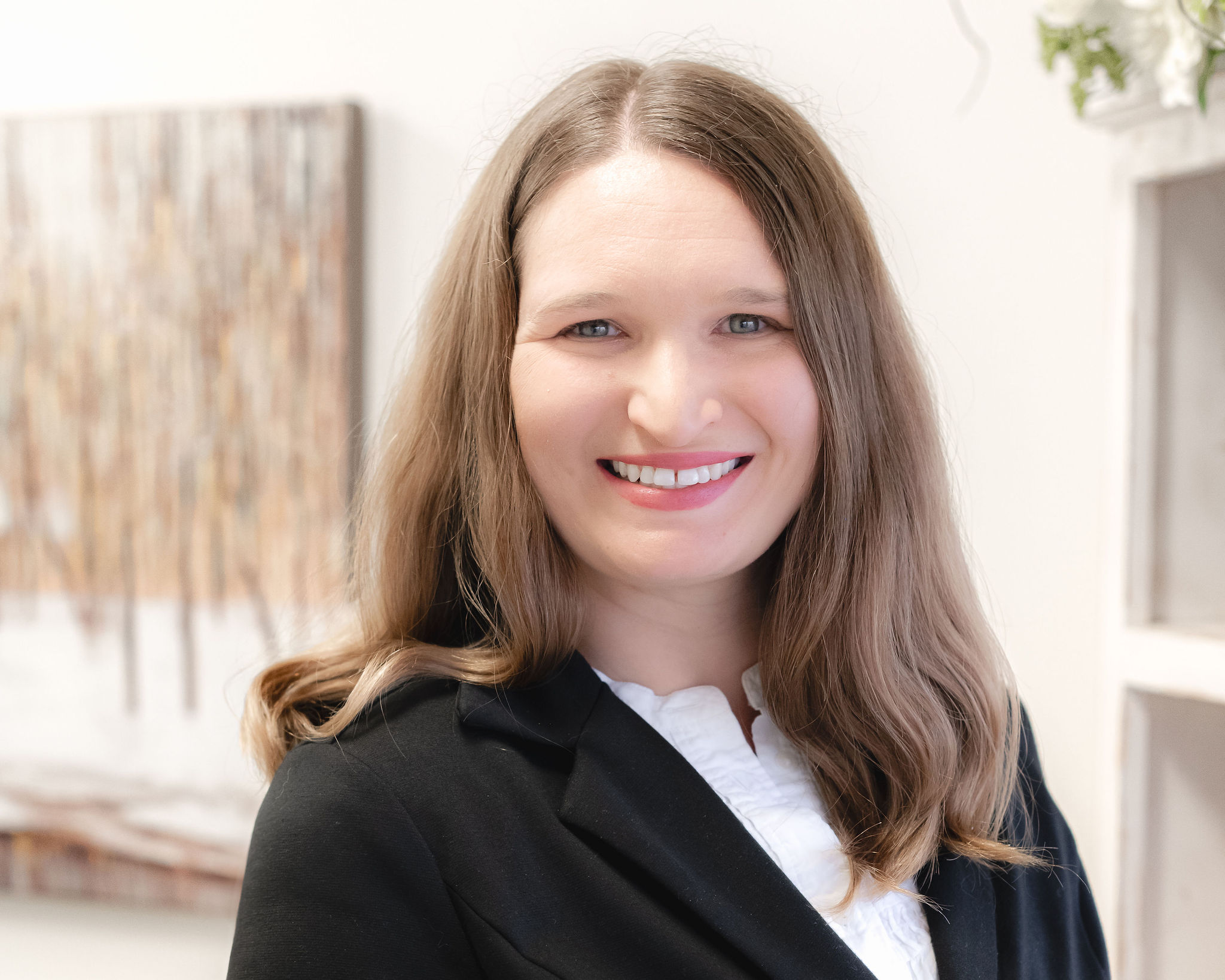 Elizabeth O’Malley, LMFT, smiling in a black blazer with soft waves and a warm background