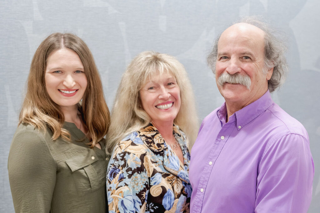 Dr. Liz O'Malley, Dr. Lori Zaremski, and Dr. Roger Light smiling together in front of a soft gray background.